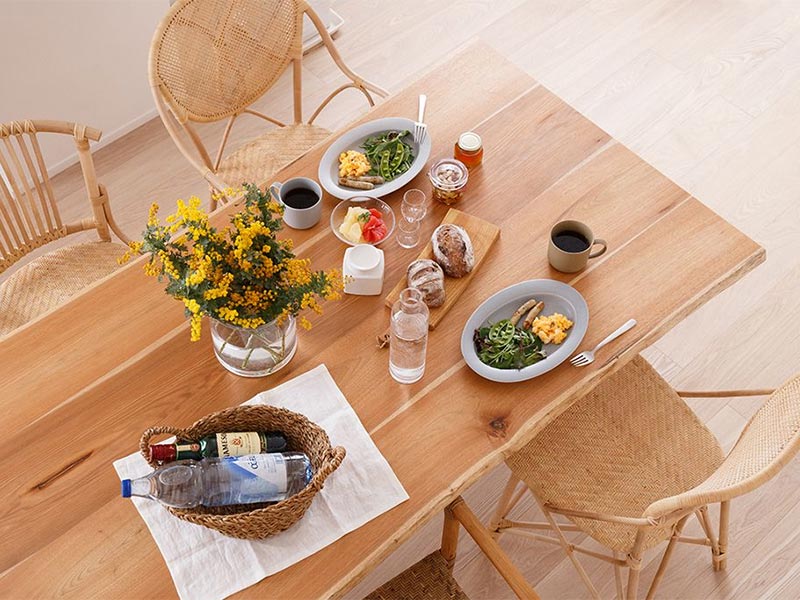 天然木のテーブルにデザイン違いのラタンチェアを並べた食卓